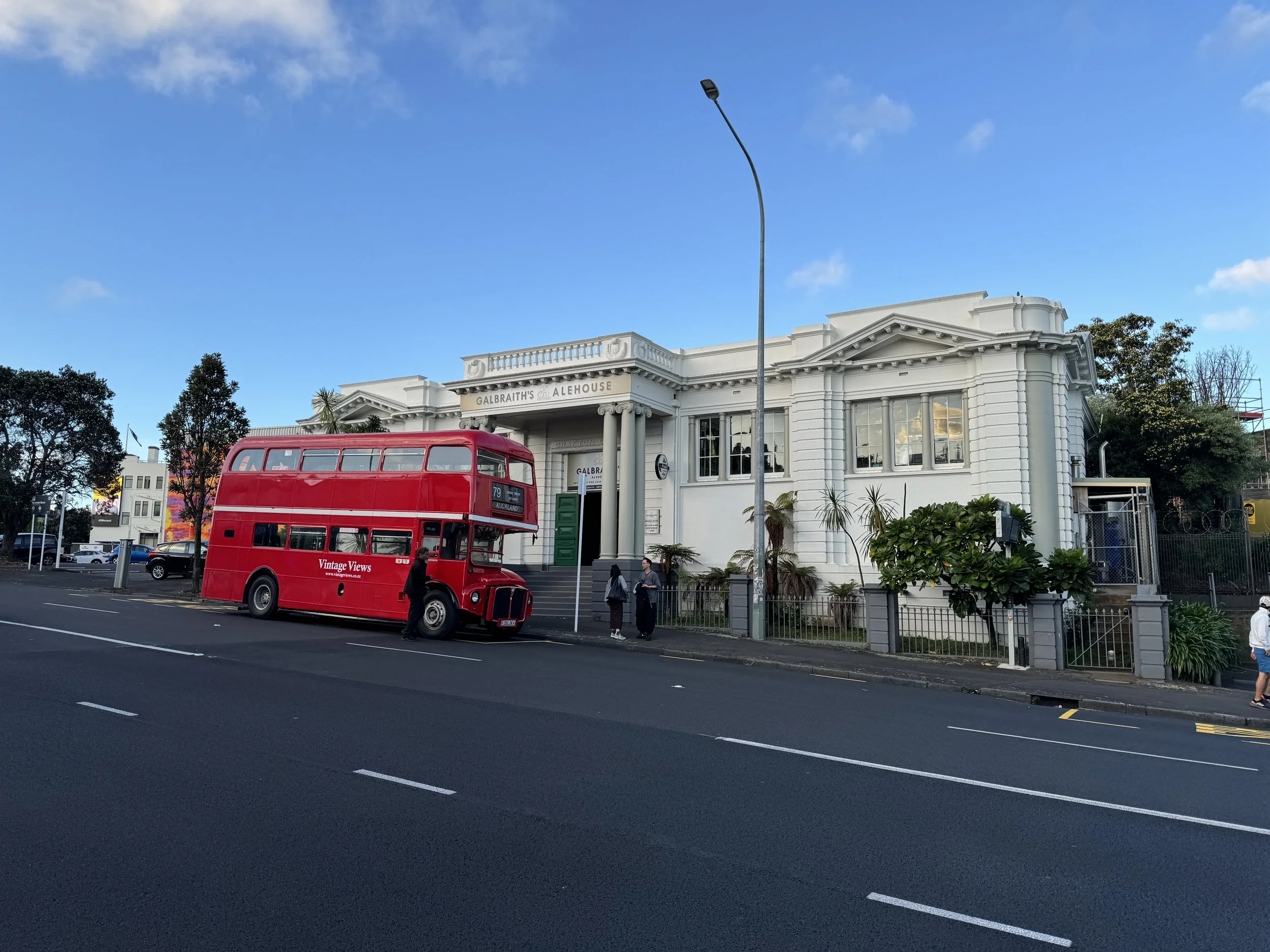 A historic white building labeled 'Galbraith's Alehouse' with a red double-decker bus parked in front.