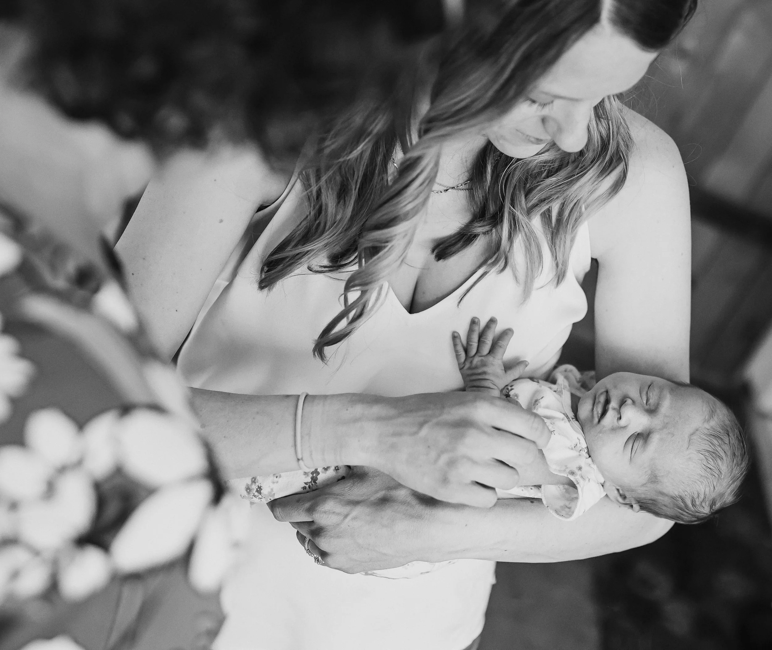 A woman cradling a newborn baby in her arms, seen from above, in a black and white photo.