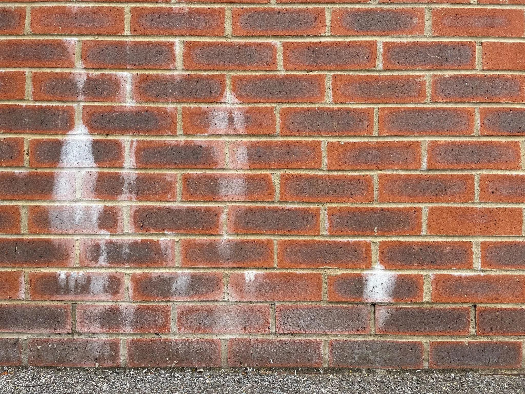 Red brick wall with white spray paint graffiti.