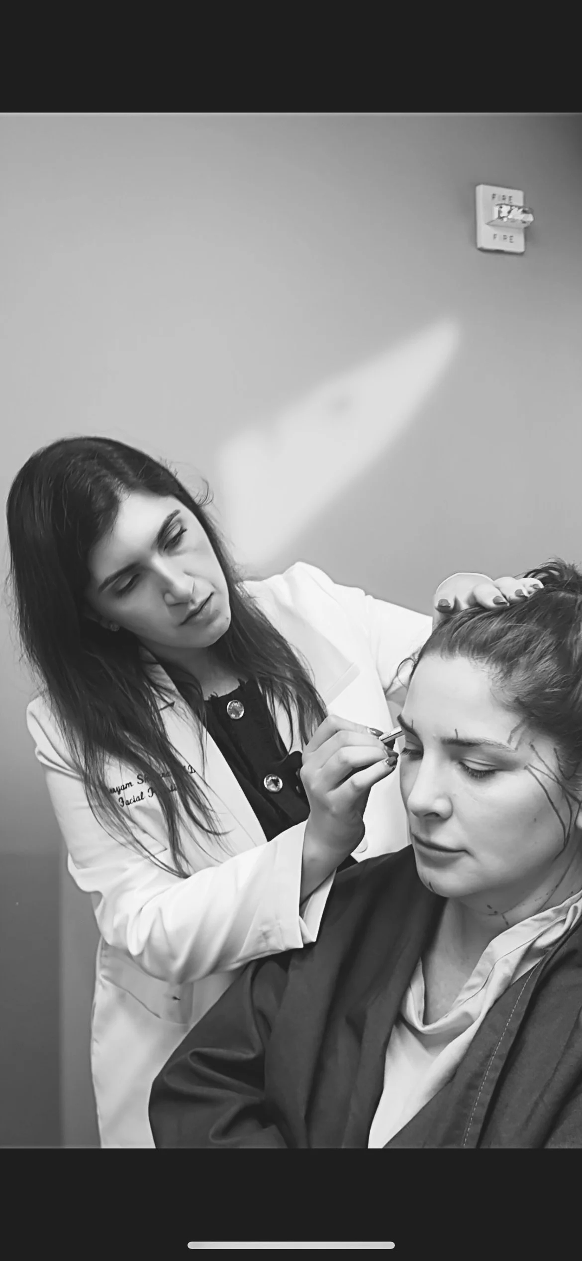 A woman is getting her Deep plane facelift surgical marking before surgery by Dr. Meryam Shikara, a Facial Plastic Surgeon in a black and white photo.