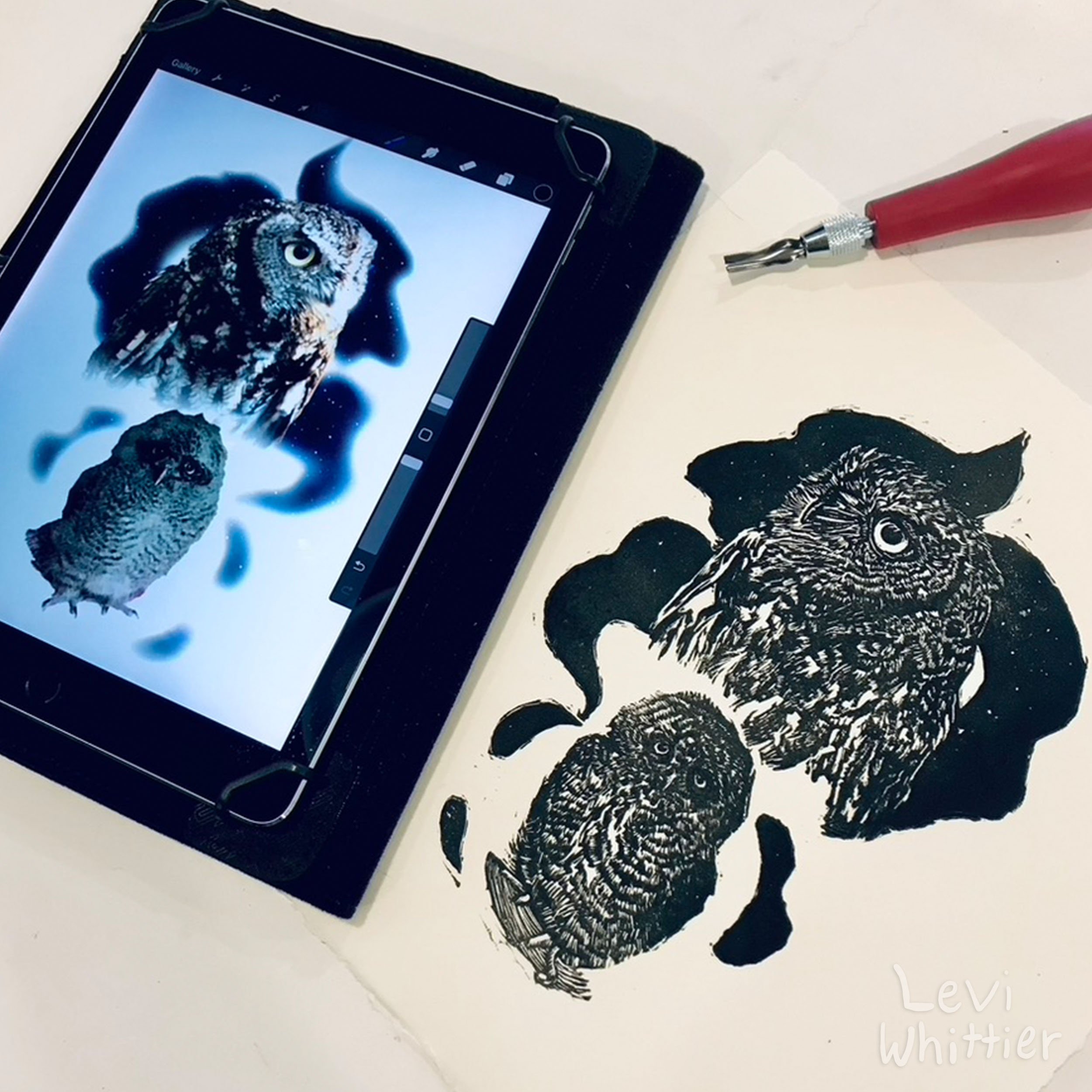 A drawing of two owls in black and white next to a tablet displaying a digital image of the same owls. The drawing is on white paper, and there is a red and silver craft tool nearby.