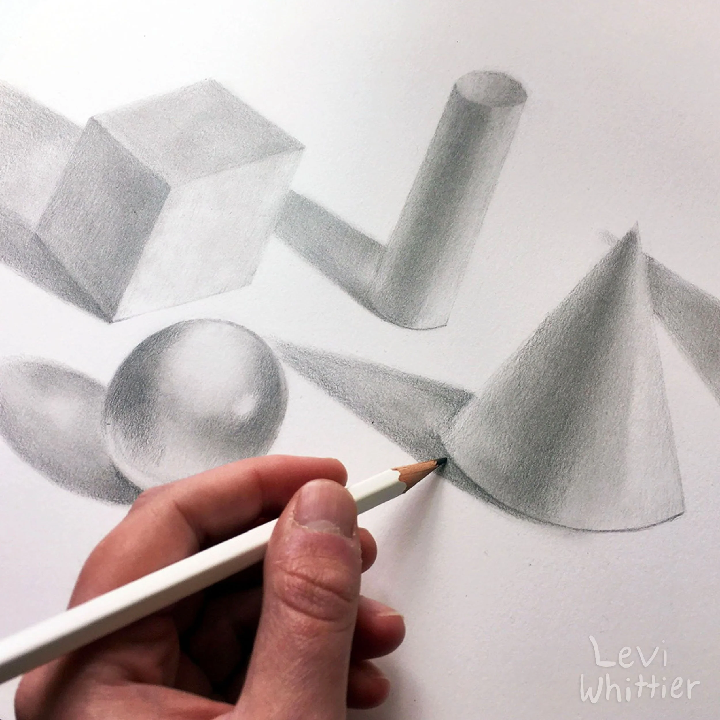 Drawing of geometric shapes including a cube, a cylinder, a sphere, and a cone in pencil on paper, with an artist's hand holding a pencil in the foreground.
