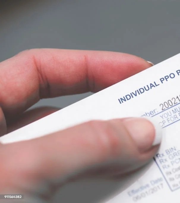 A modern building with a stone wall on a grassy hilltop, with snow-capped mountains in the background under a cloudy sky.