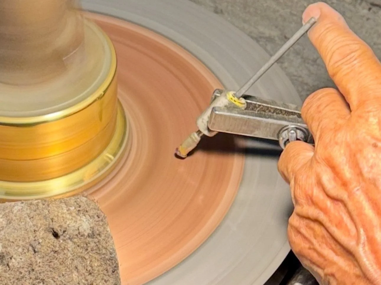 A person cutting and polishing gemstones on a rotary grinding wheel.