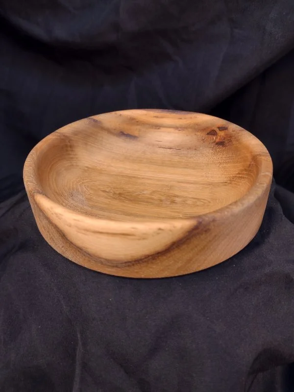Wooden bowl on black fabric background.