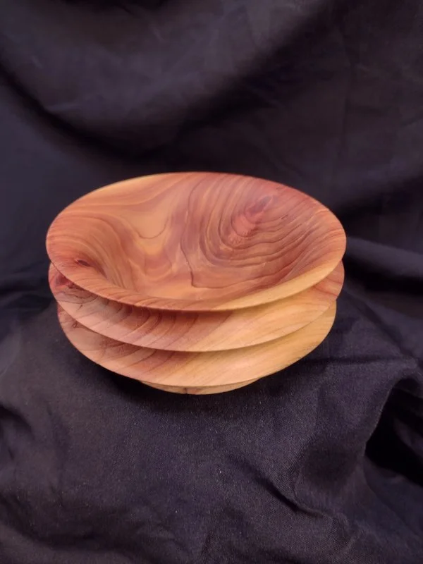 Stacked wooden bowls with a natural wood grain finish on black fabric background.