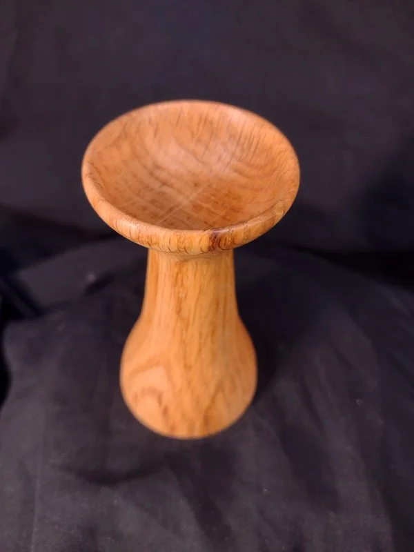A small, wooden, pedestal-style bowl with a rounded top and a short, curved base.