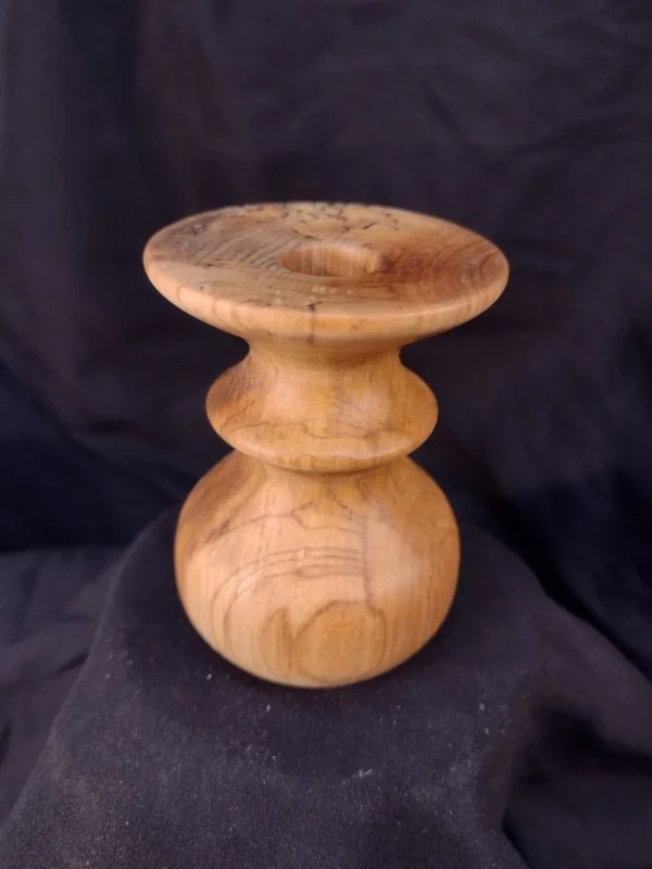 Turned wood with unique shape and central hole.