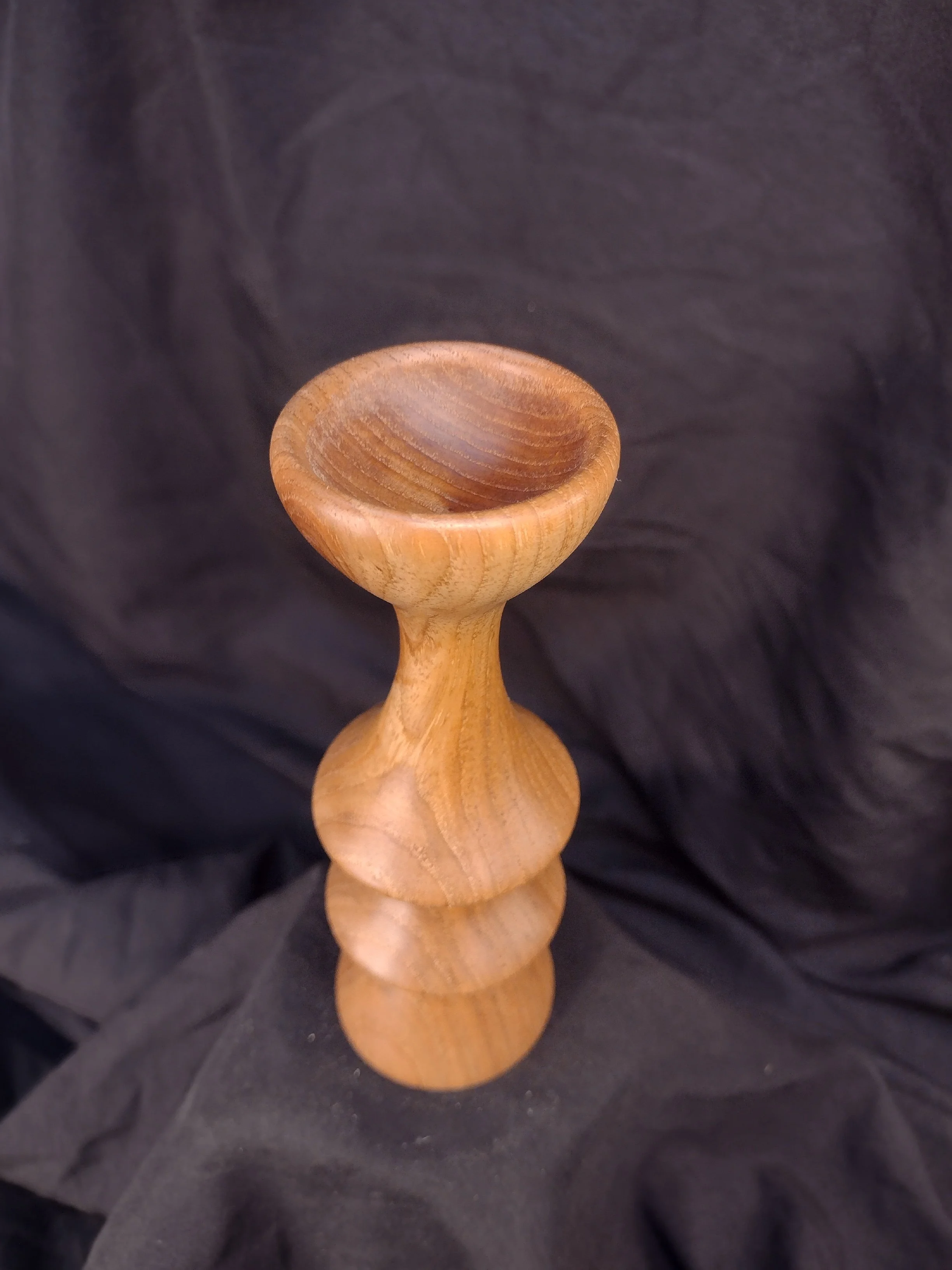 A wooden goblet with a rounded bowl and a short stem.