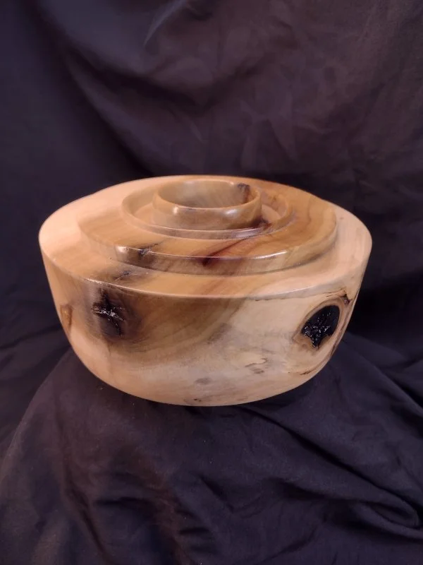 Wooden nested bowls with a natural finish on black fabric background.