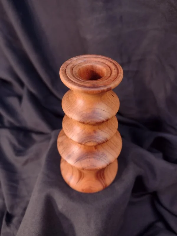 Turned wood with unique shape and central hole.