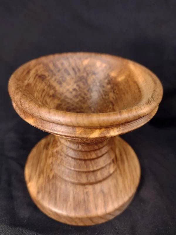 A small wooden pedestal bowl with a rounded top and a wider base, made of polished light brown wood with visible grain patterns.