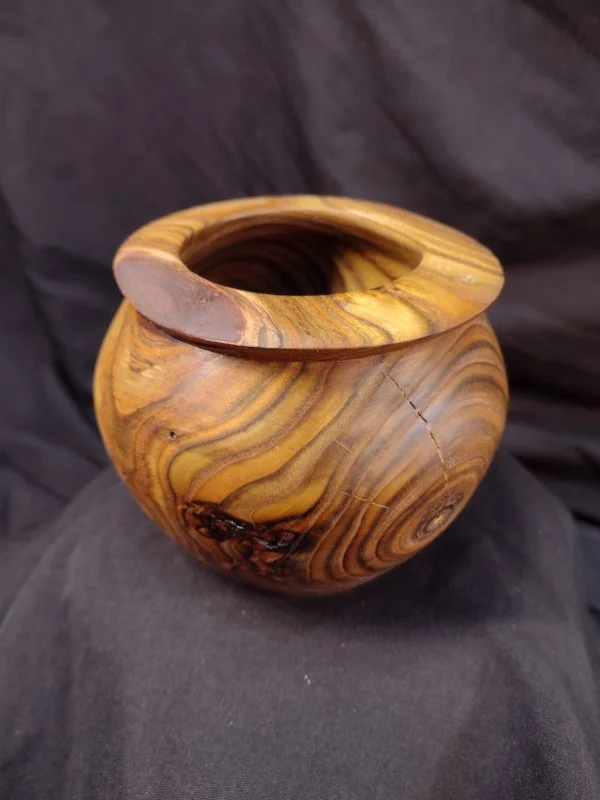A small wooden vase with a rounded shape and a wide opening at the top, featuring natural wood grain patterns and coloration.