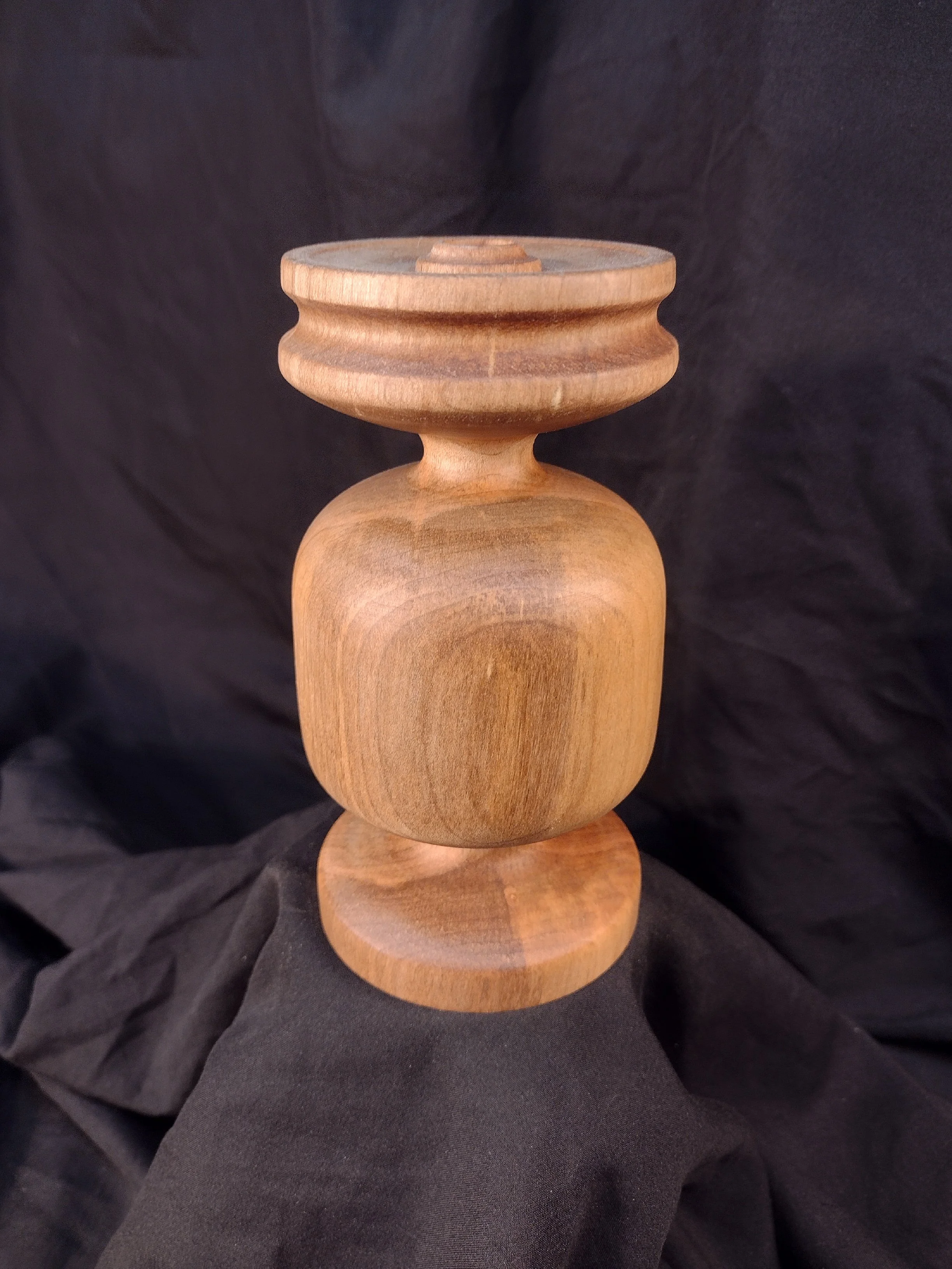 Turned wood with unique shape and central hole.