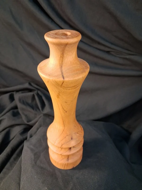 A wooden feather-shaped object with a rounded top and a carved base.