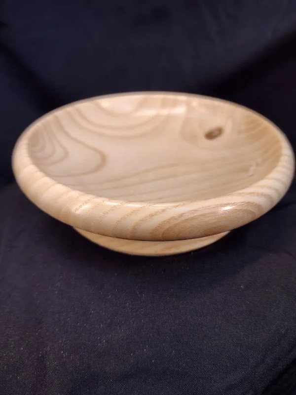 Empty wooden bowl placed on a black fabric surface.