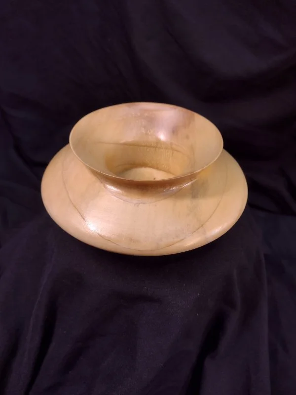 A decorative wooden bowl with a smaller bowl nested inside, placed on a black fabric background.