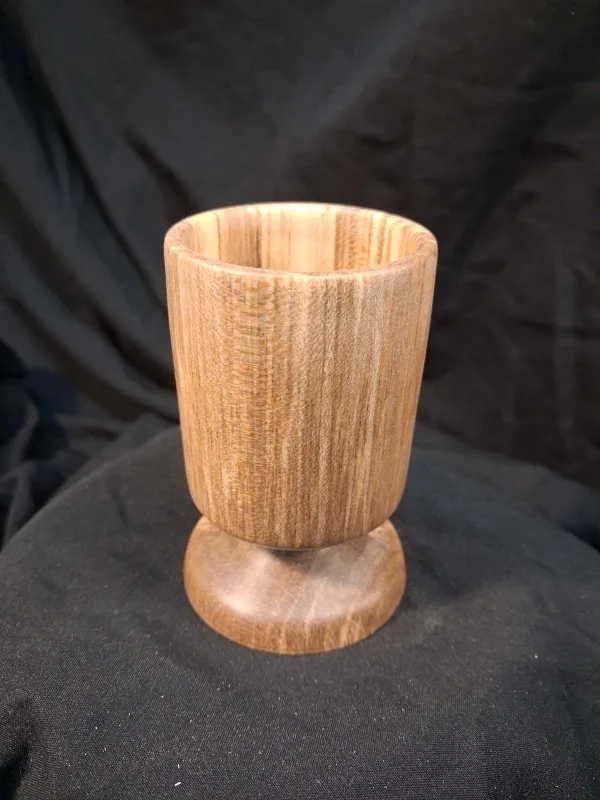 Wooden cup with a round base placed on a black surface