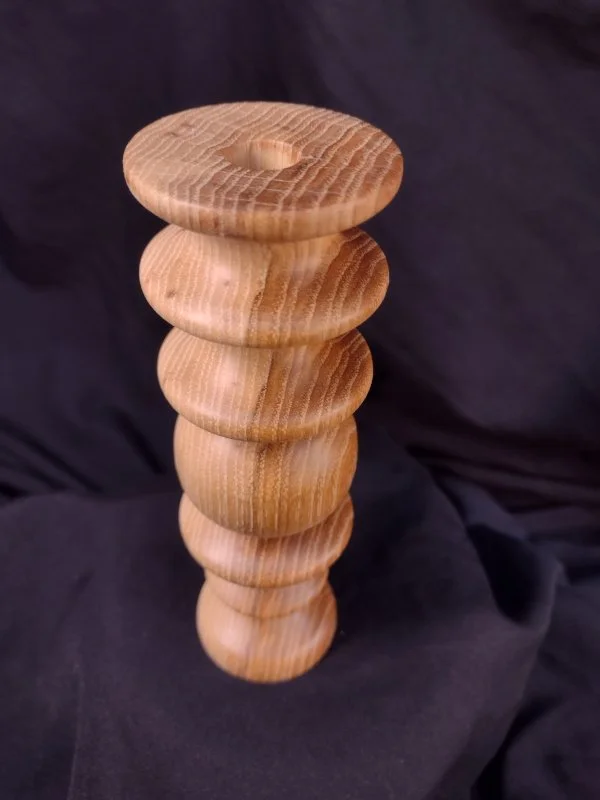 Stack of rounded wooden discs placed vertically on a black fabric background.