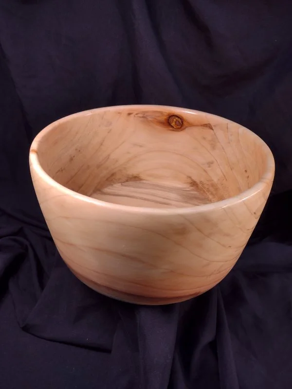 A turned wood bowl with beautiful grain and color with a natural finish.