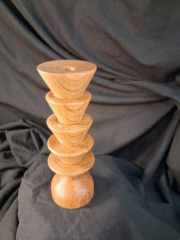 Stack of six wooden bowls, with the largest at the bottom and decreasing in size upward, against a dark fabric background.