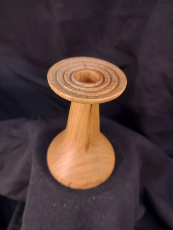 Turned wood with unique shape and central hole.