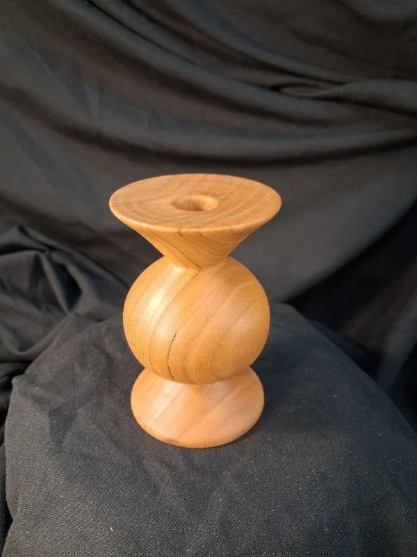 A wooden decorative object with a rounded base and a flared top, possibly a candle holder or sculpture.