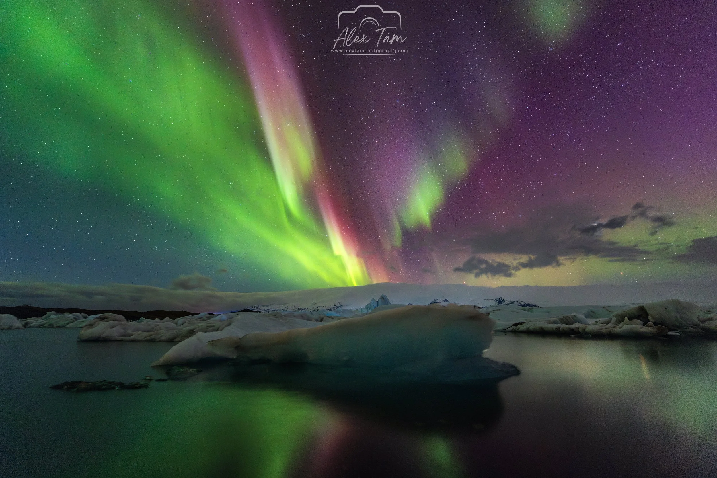 Aurora borealis lights illuminating the night sky over a body of water with icebergs.