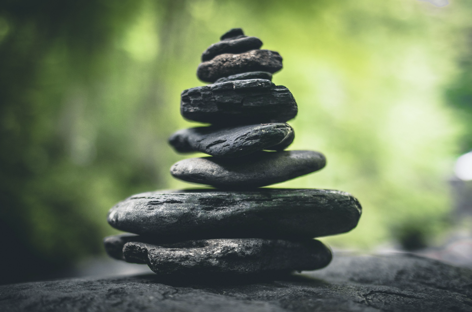 Stacked black stones outdoors with a blurred green background.