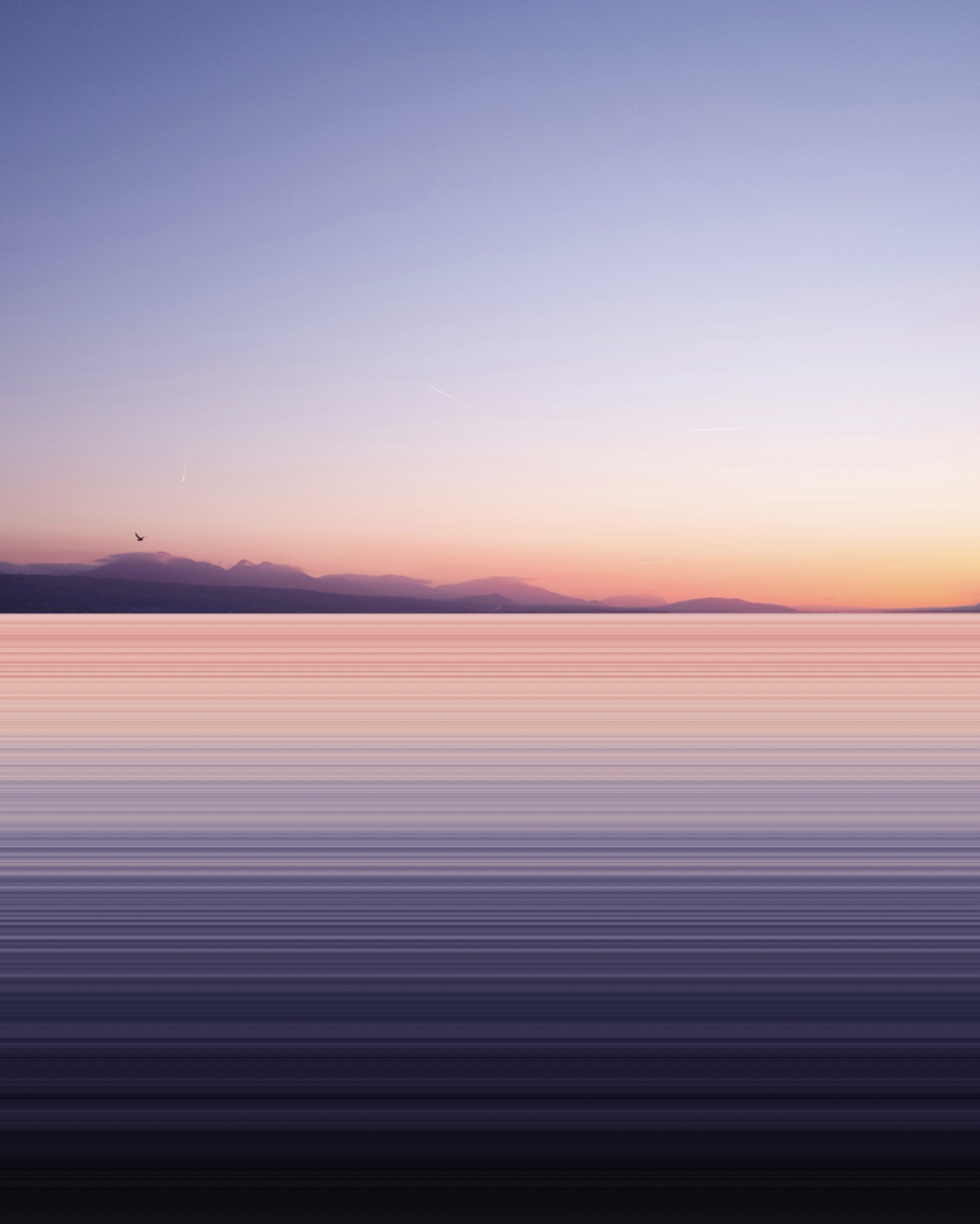 Colorful sunset over a body of water with mountains in the distance and a bird flying in the sky, communicating calm, serene, peaceful
