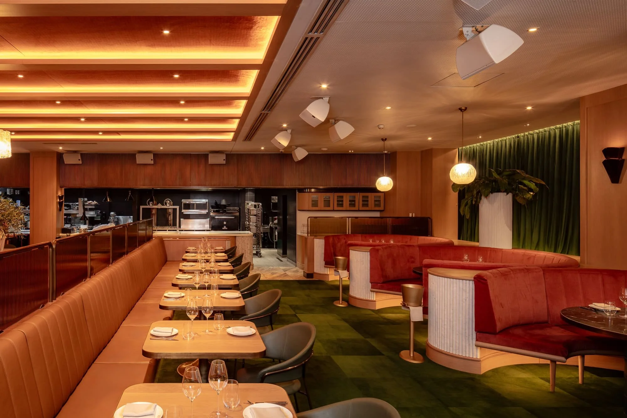 Interior of a restaurant with wooden walls, green curtains, and warm lighting. 