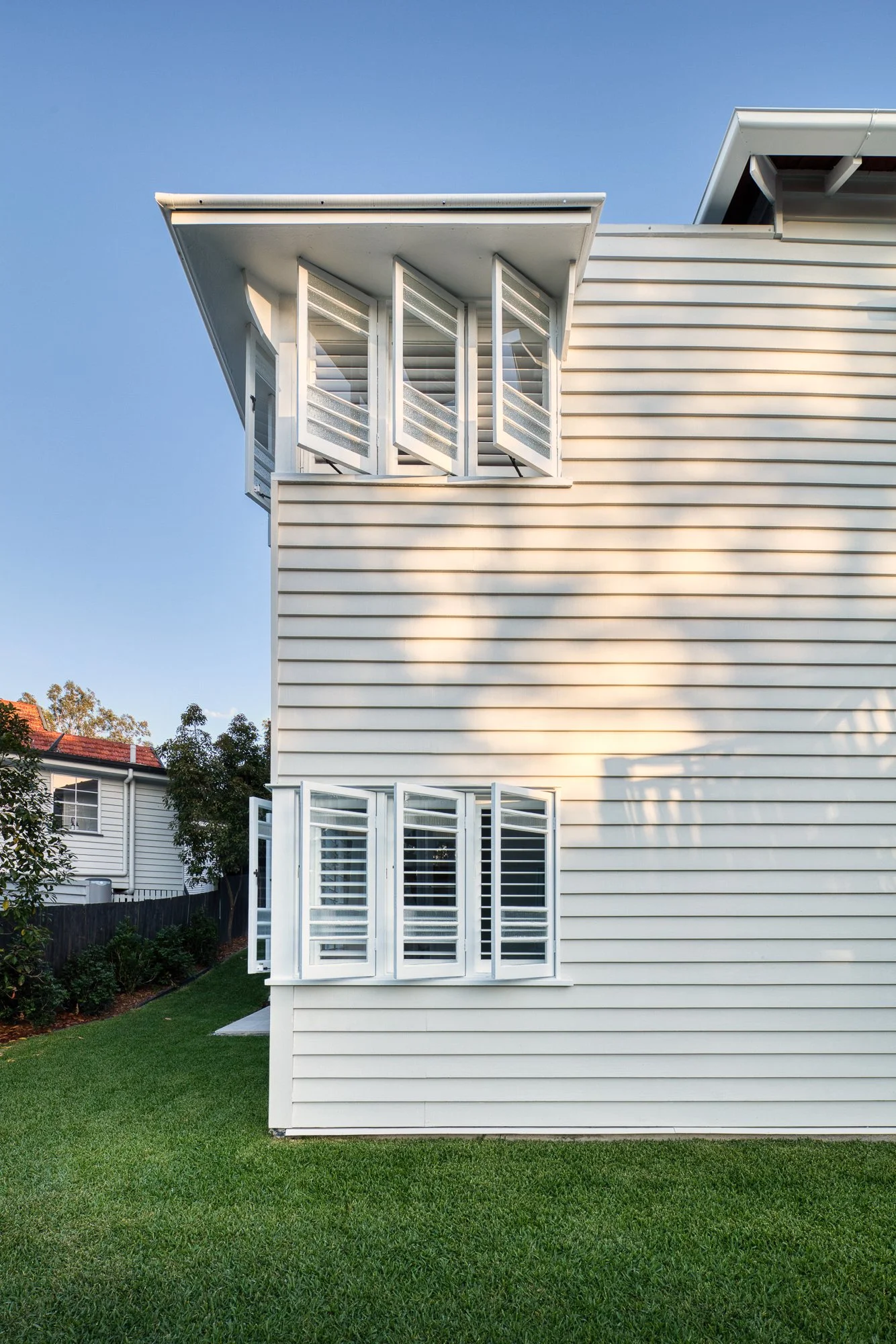 A white house with horizontal siding and open shutters on the windows