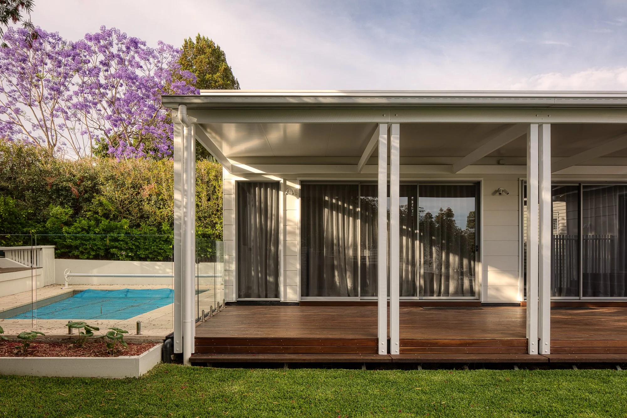 A backyard with a small wooden deck, large sliding glass doors, and a white house exterior. 