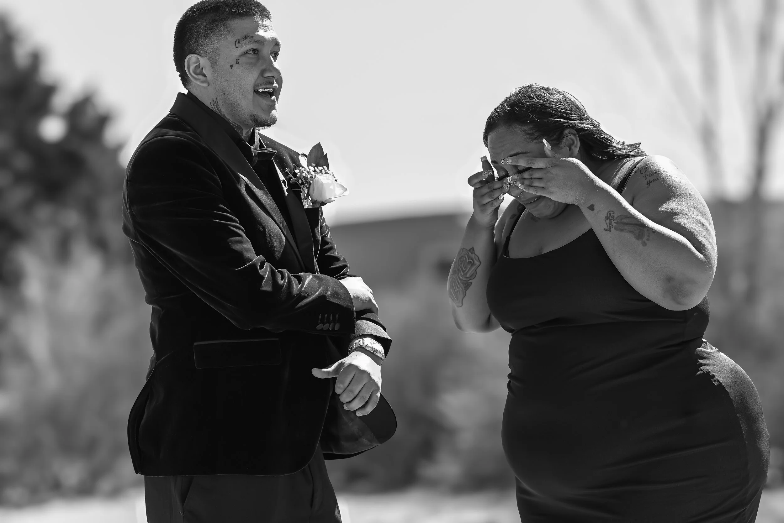 A man in a tuxedo holding hands with a woman, who is visibly emotional and wiping tears away. The scene appears to be a wedding or special event.