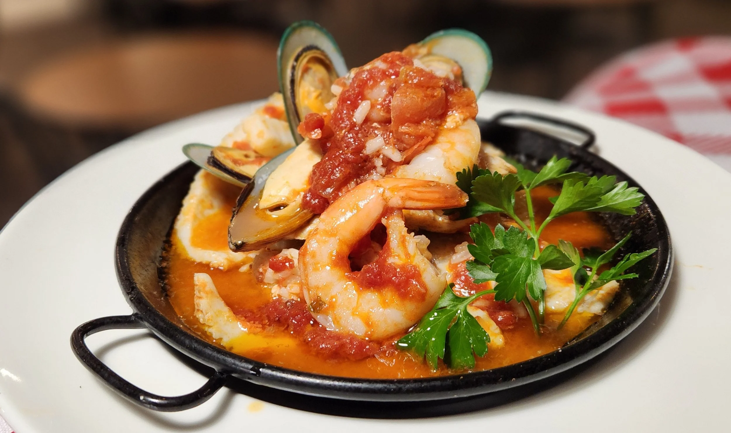 Seafood stew with shrimp, mussels, and fish in a tomato broth, garnished with fresh parsley.