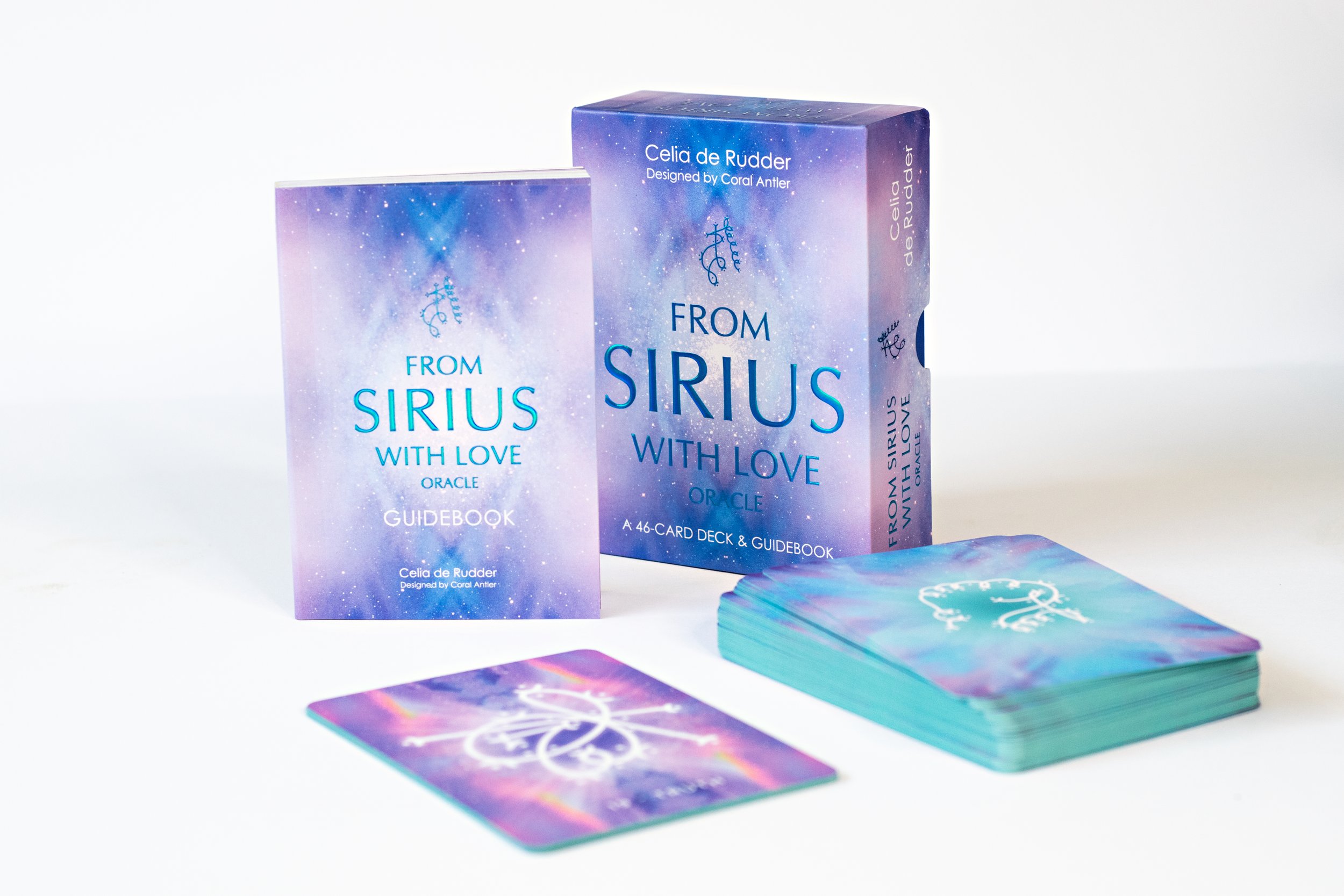 Deck of cards, guidebook, and fanned-out cards for the "From Sirius With Love" oracle deck by Celia de Rudder, with a galaxy-themed design.
