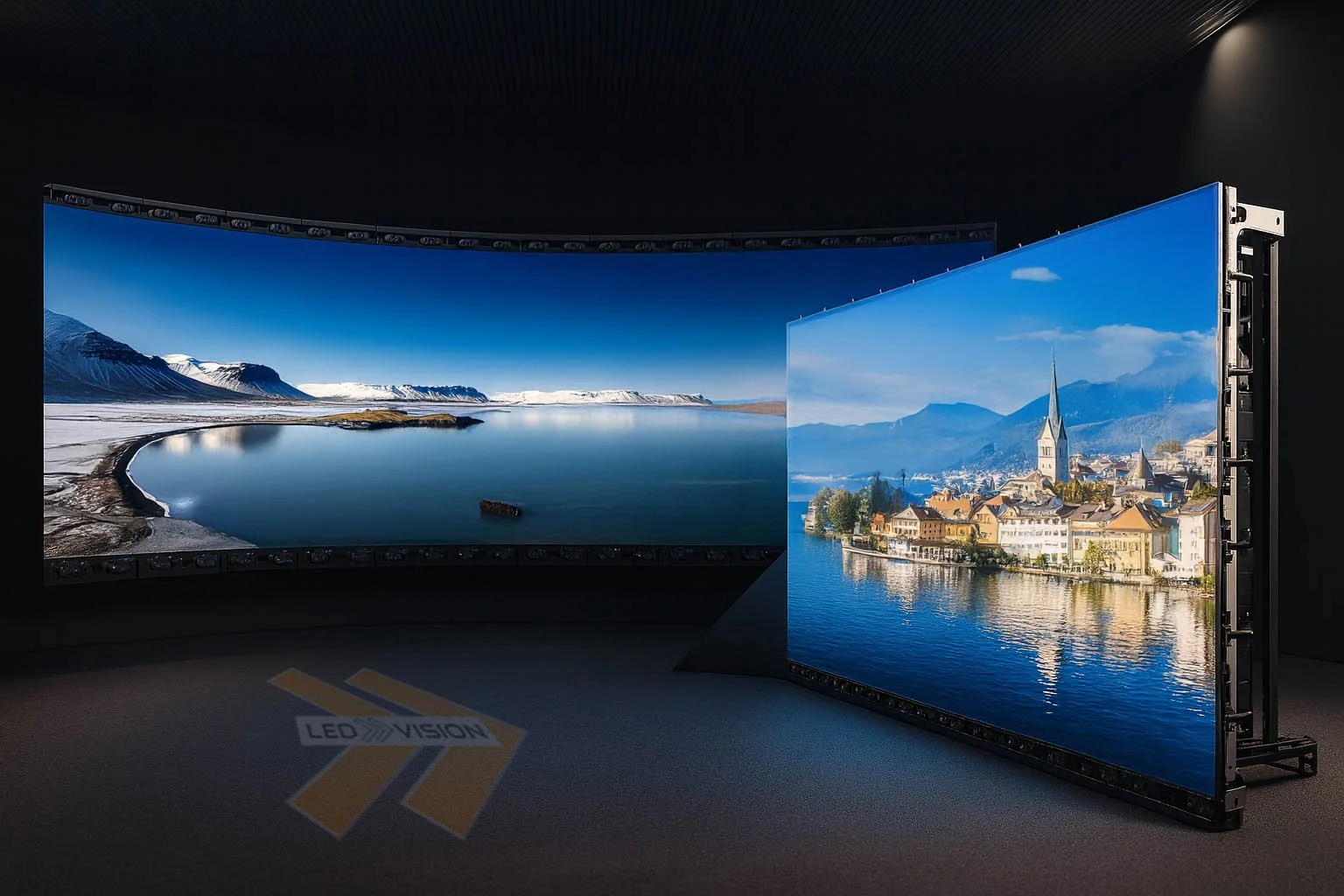 Two large LED screens displaying scenic landscape images, one showing a lake and mountains, the other showing a town with water and mountains in the background, inside a dark room with a carpeted floor marked 'LED VISION'.