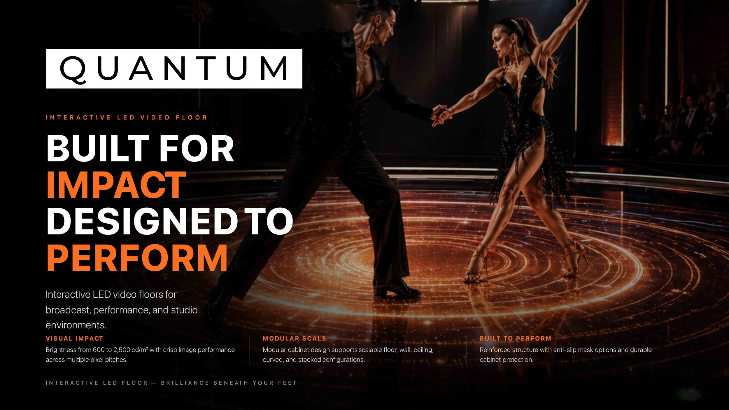 A dance couple performing on an interactive LED floor with orange and gold light effects, in a dark studio with an audience in the background.