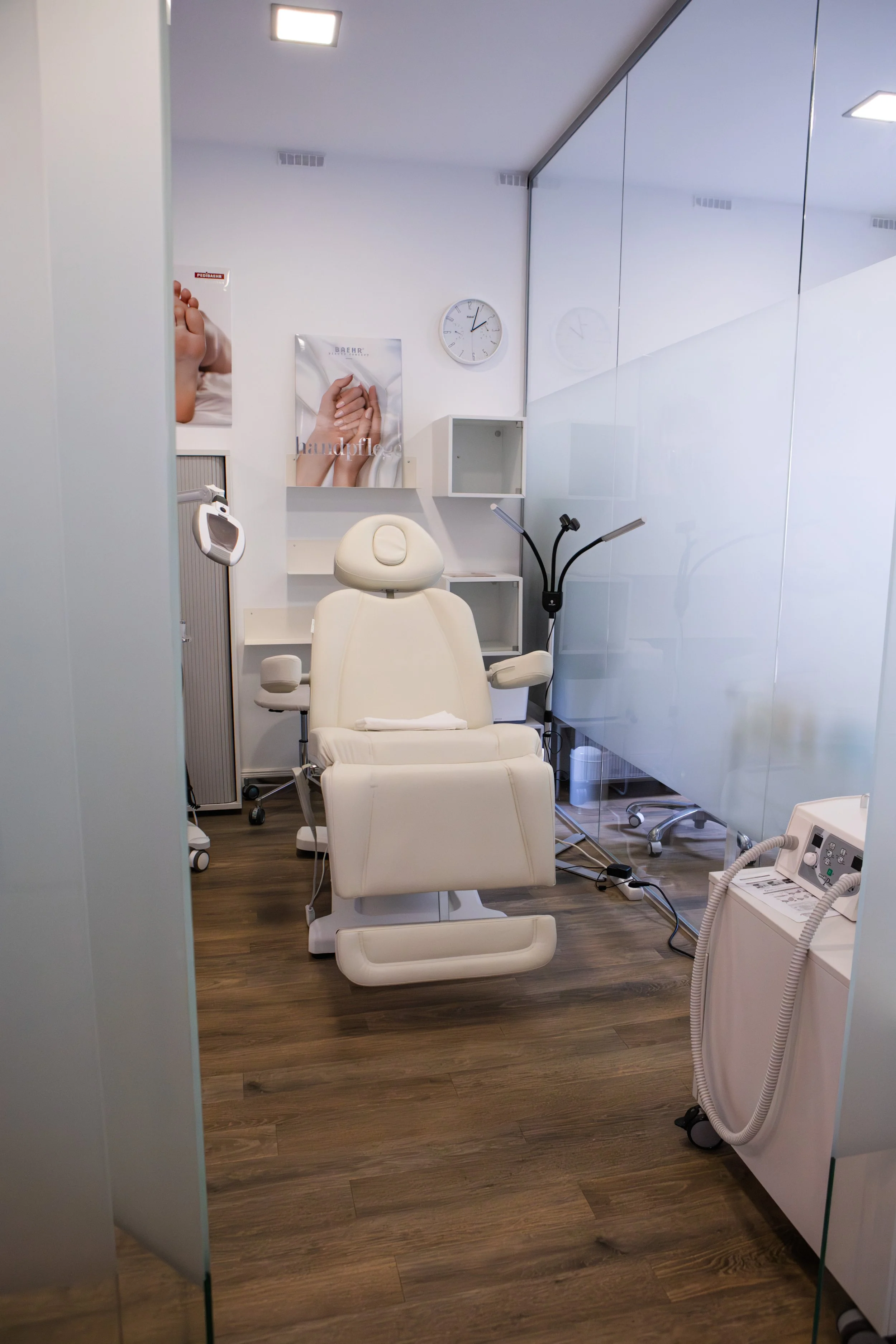 Ein bequemer, weißer Behandlungsstuhl in einem modernen medizinischen Raum, umgeben von medizinischen Geräten, Regalen und einem Wandbild mit Händen, die sich halten.