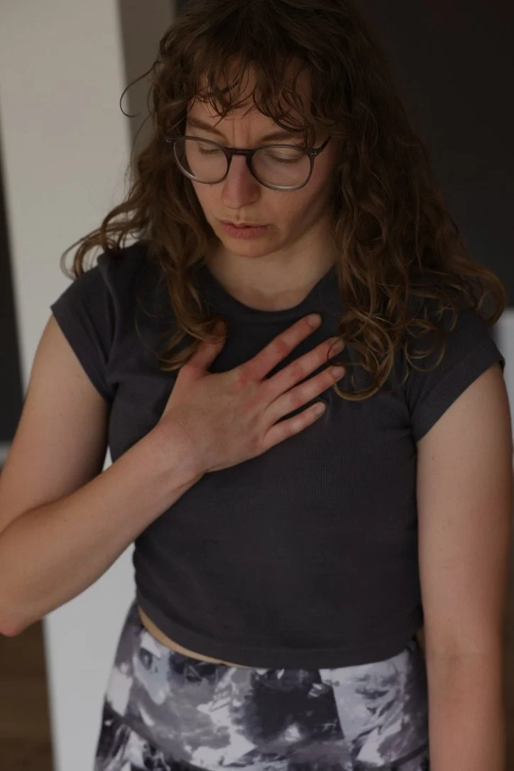 Kvinde med briller, der holder hånden på brystet, ser bekymret ud.