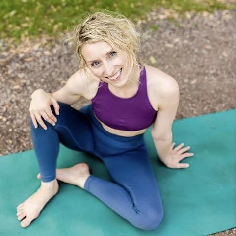 Kvinde laver yoga udendørs på grøn yogamåtte