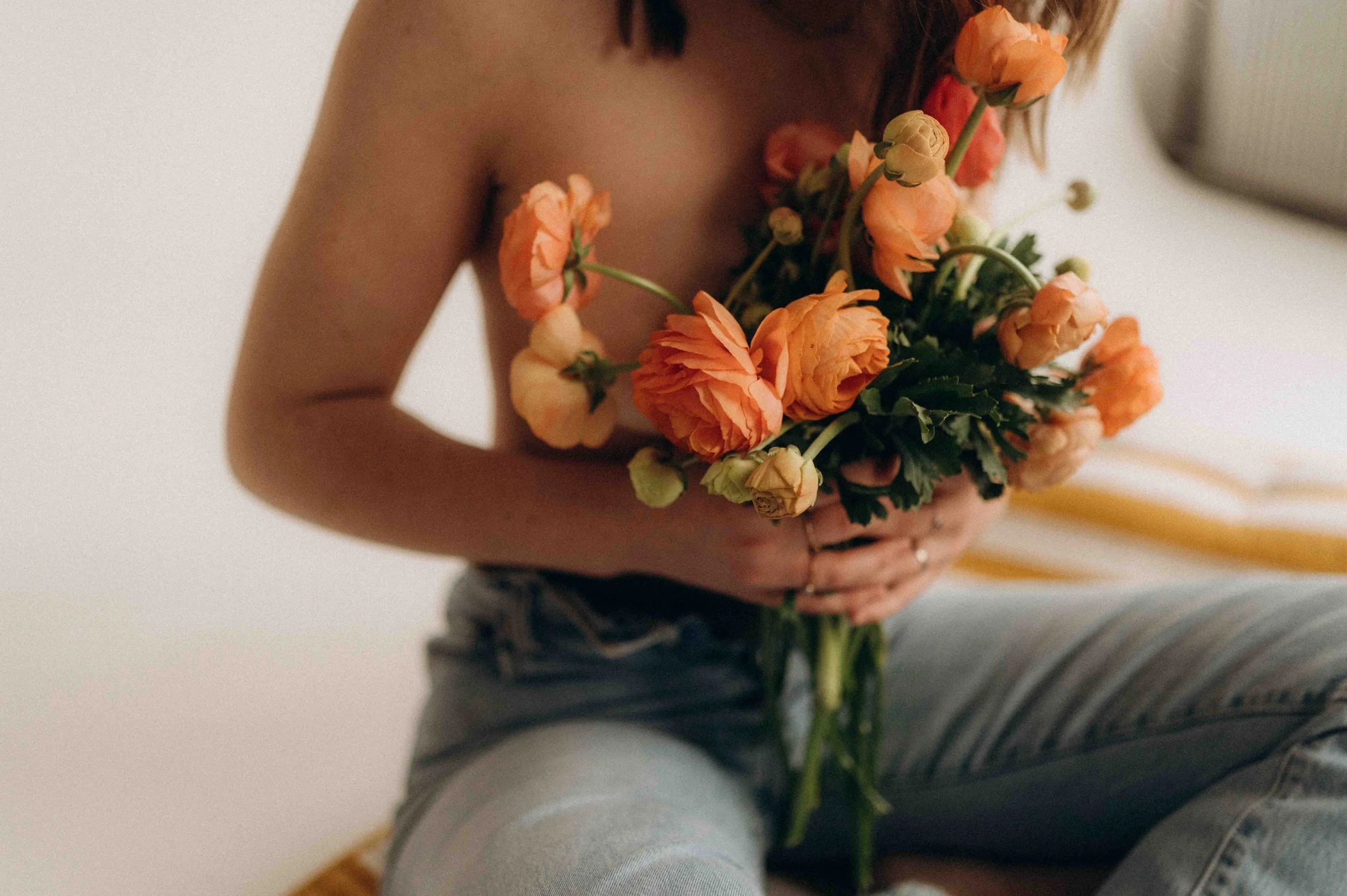 a woman holding orange flowers in jeans