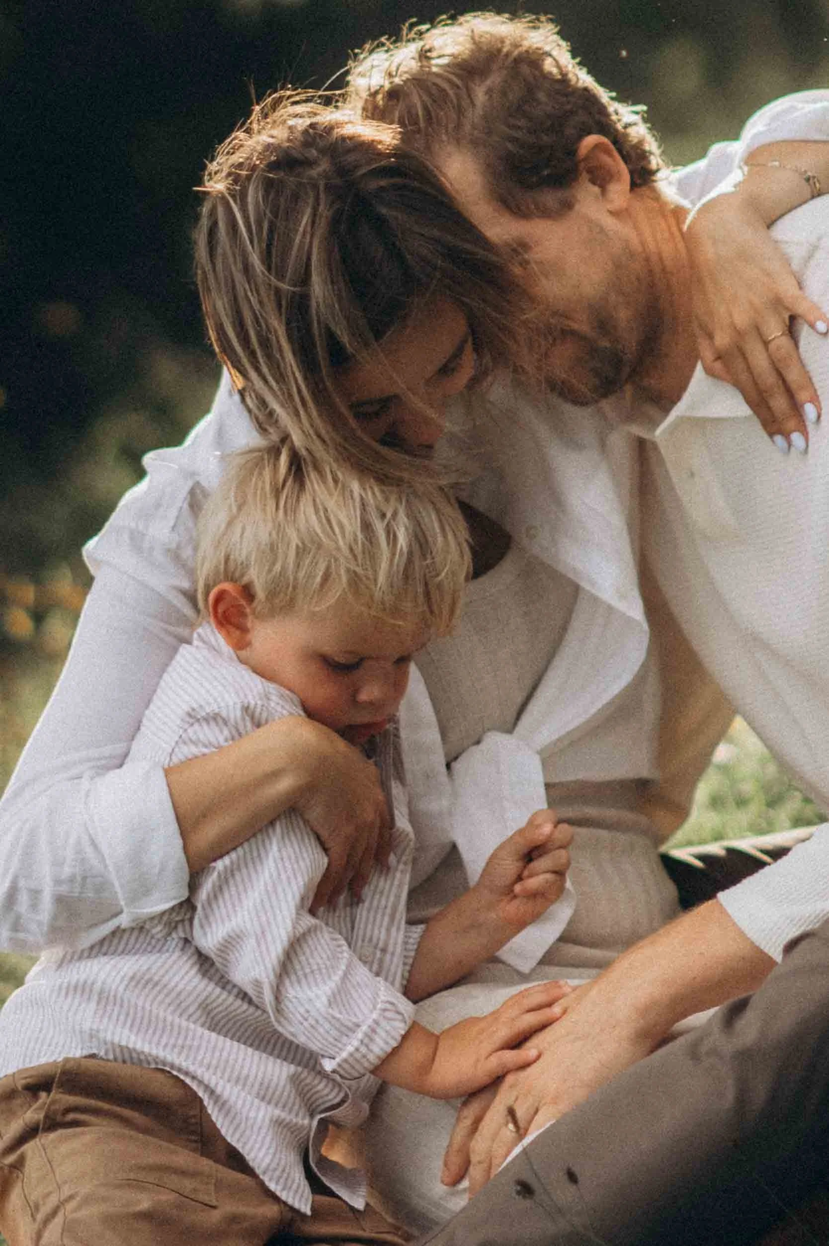 a mother, father & son holding each other, hugging
