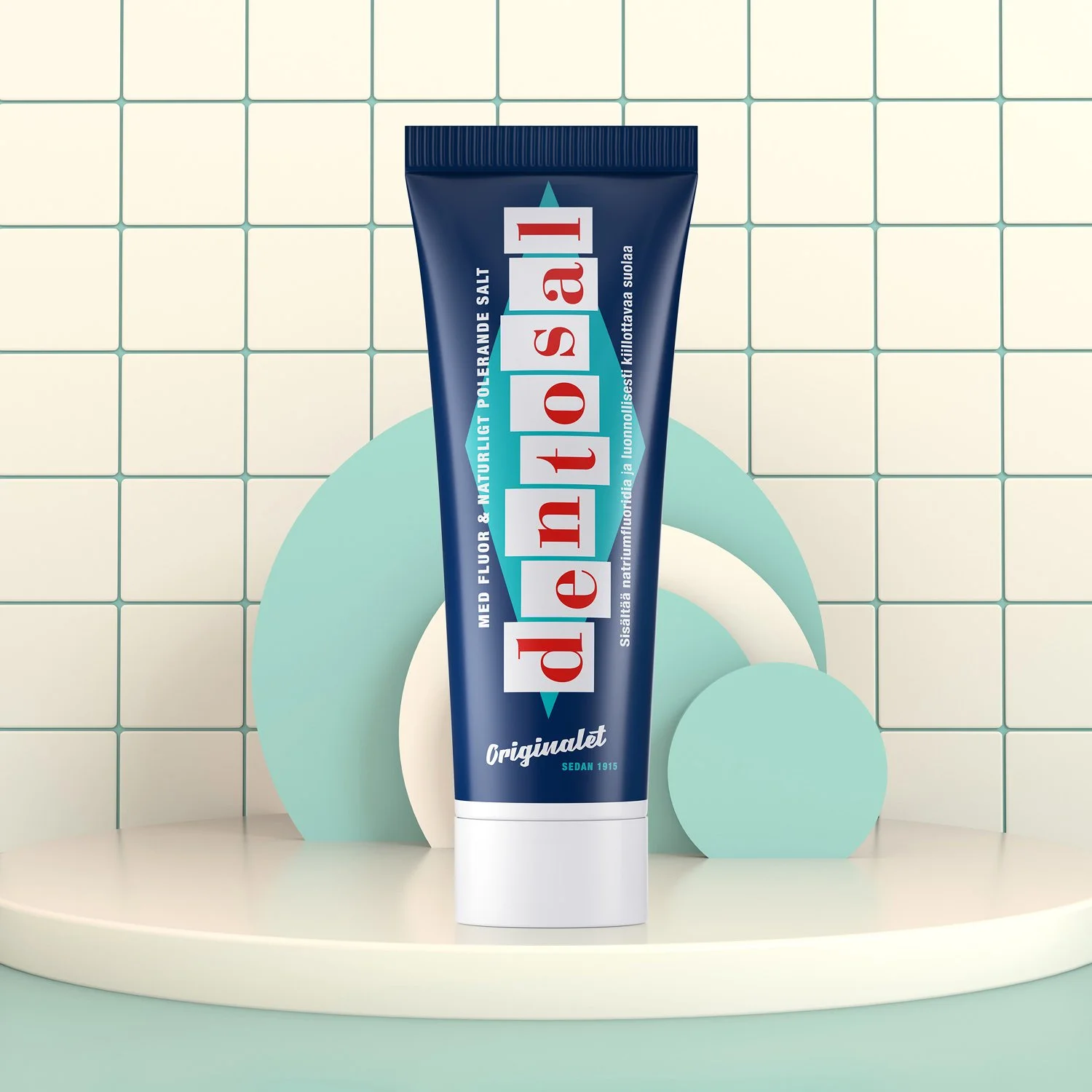 A tube of Denitol med fluoride toothpaste standing upright on a white round platform with geometric pastel-colored decorations and a tiled wall background.