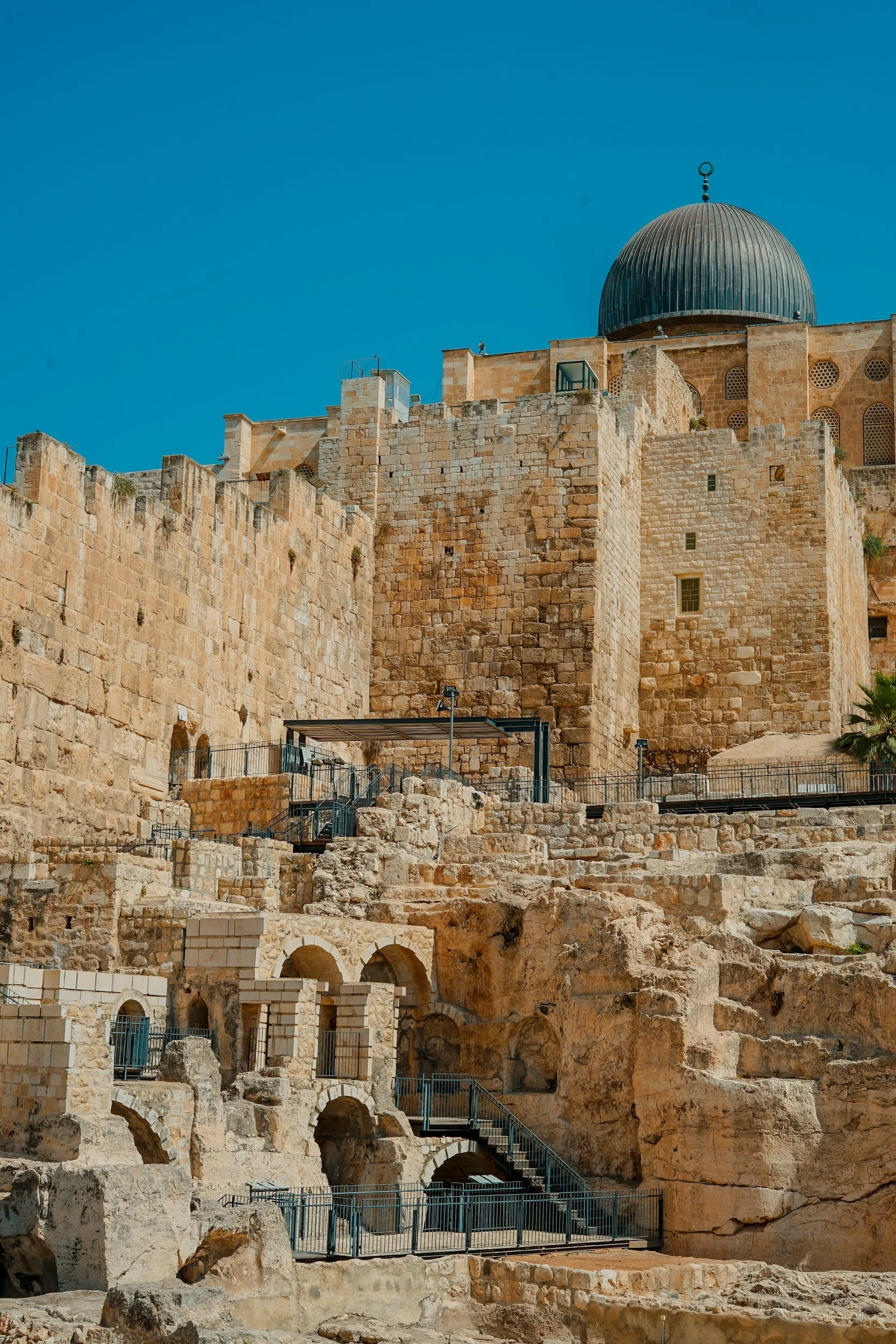 Ancient stone fortress with a dome on top, built with large beige stones, under a clear blue sky.