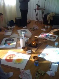 Art class setup with paintings and supplies scattered on a wood floor