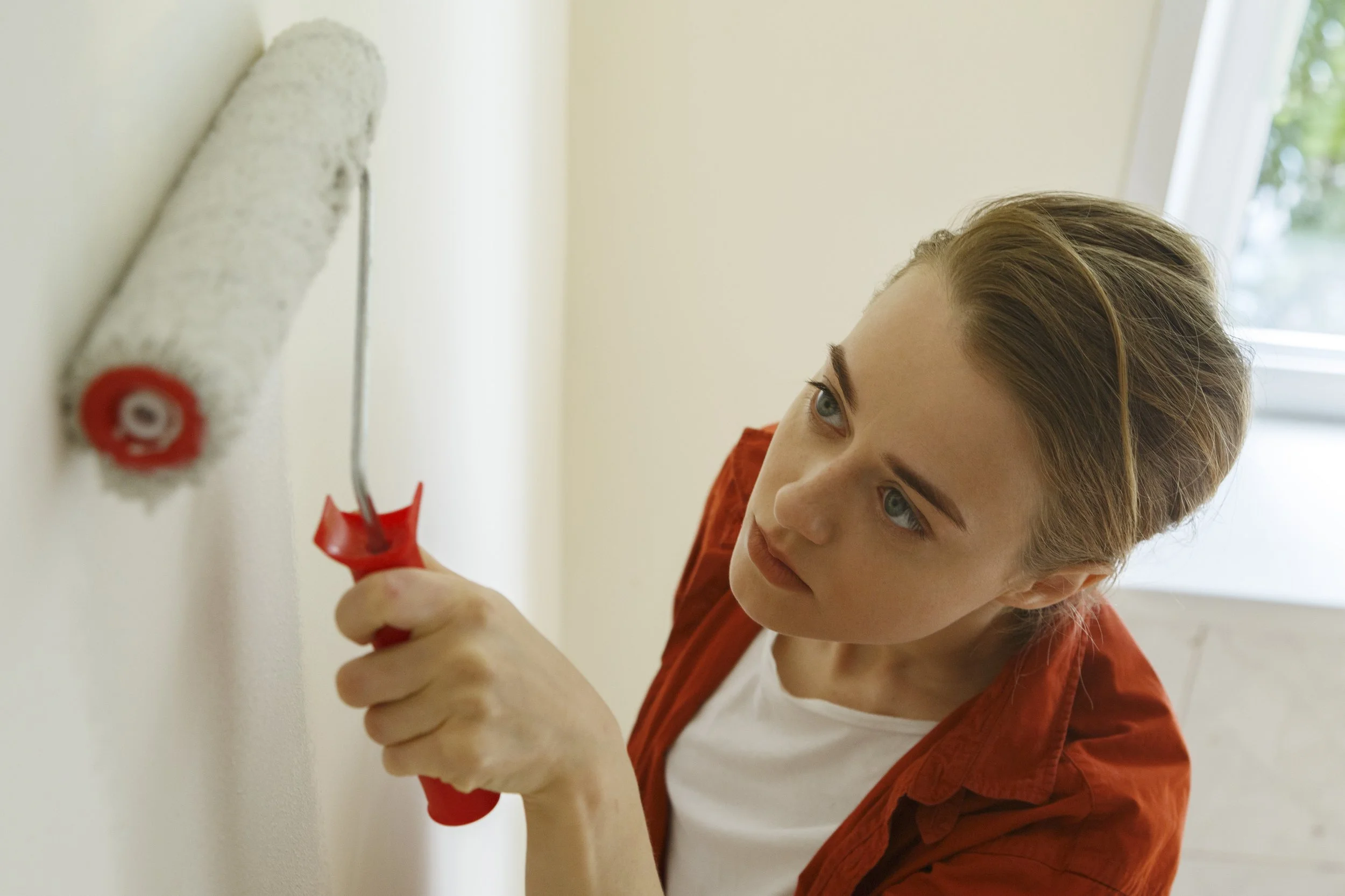 Donna mentre dipinge le pareti di grigio con il rullo