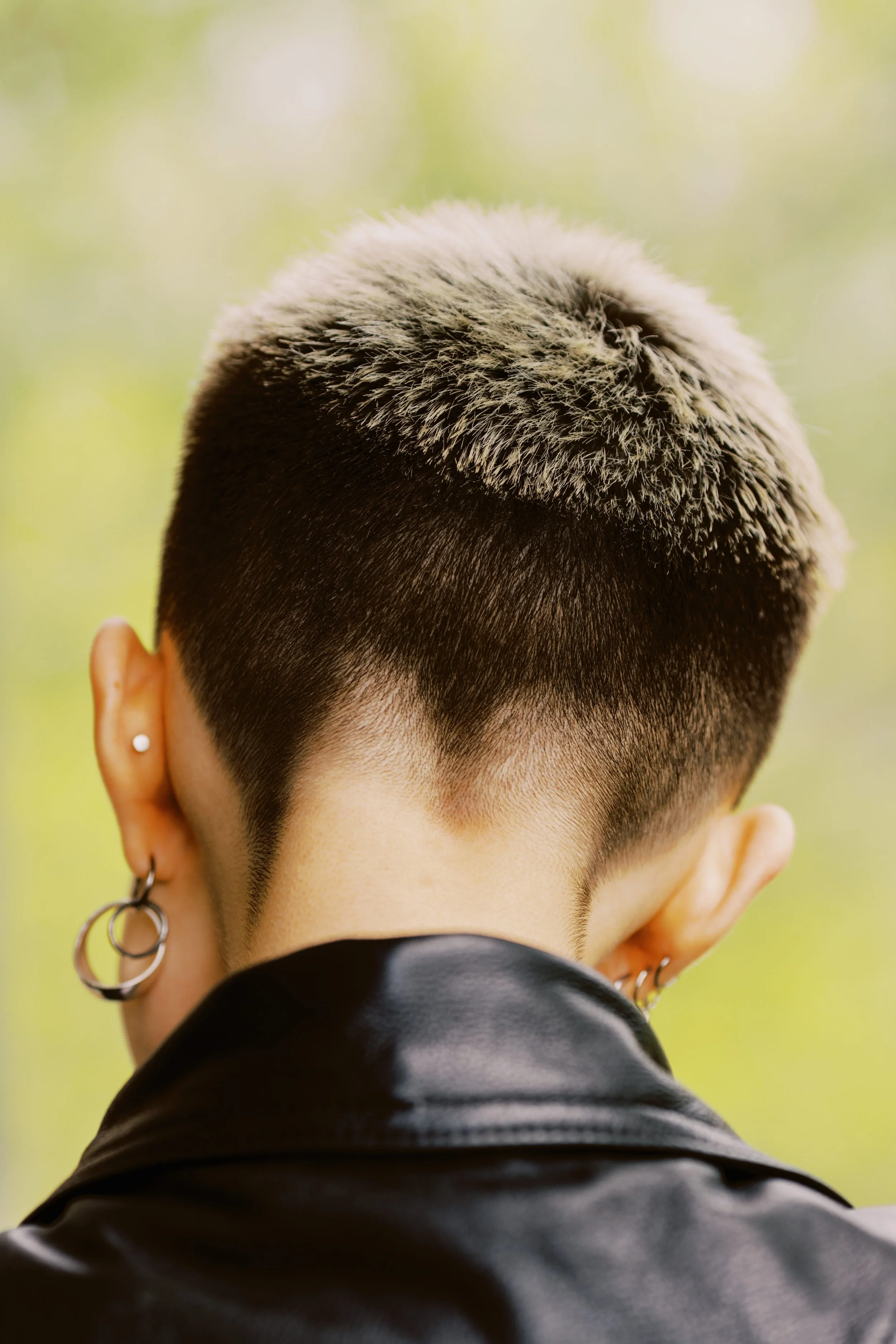 Espalda de mujer con cabello corto que lleva una chaqueta de cuero