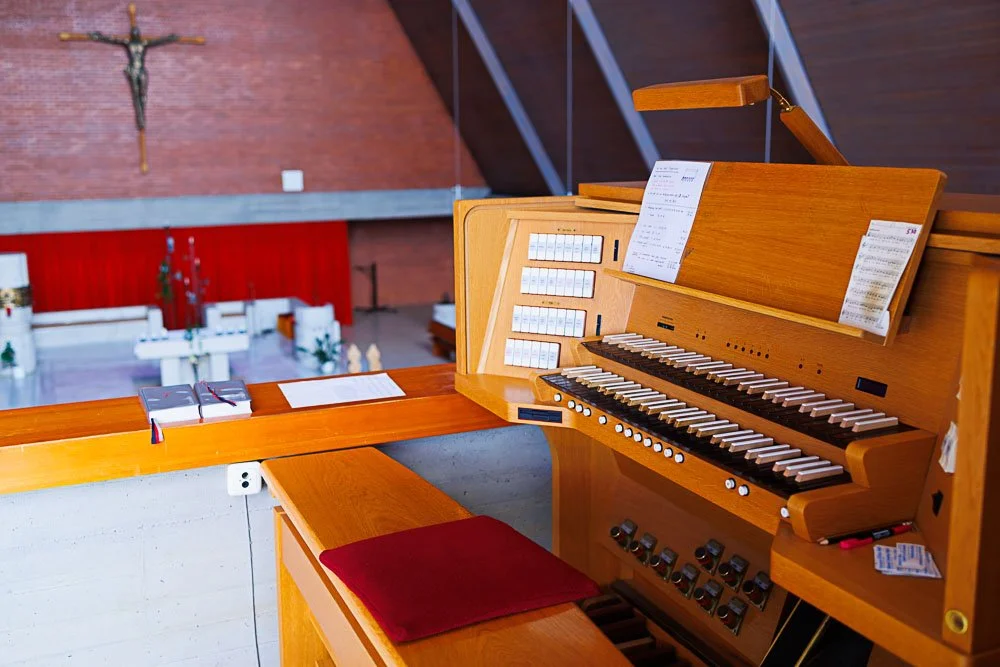 Orgel in einer Kirche mit einem Kreuz an der Wand dahinter.
