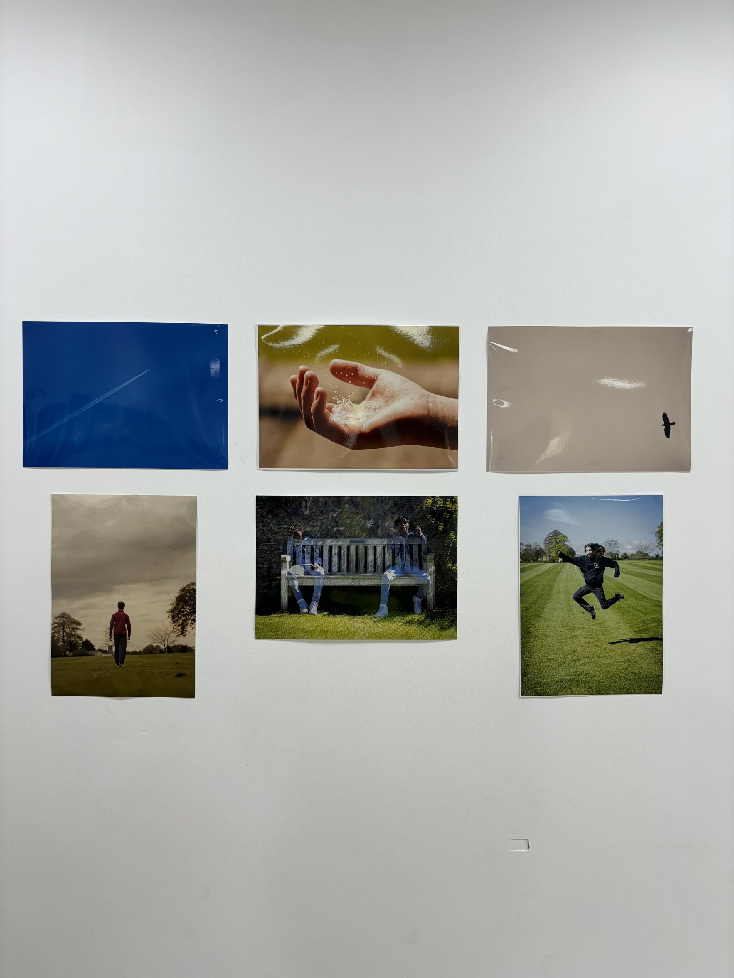 Six photographs arranged in two rows on a white wall. The top row has images of a jet trail in a blue sky, a hand catching water, and a bird flying in a gray sky. The bottom row shows a person walking on a field, two people sitting on a park bench, a
